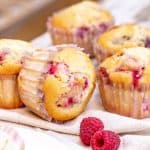 Several raspberry muffins on grey beige surface.