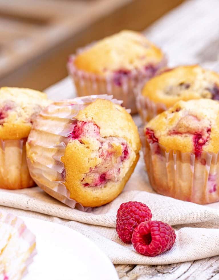 Several raspberry muffins on grey beige surface.