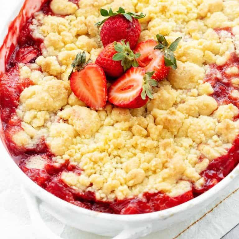 Overview close up of white oval dish with strawberry dump cake topped with fresh strawberries.