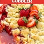 Pink white text overlay over close up image of juicy strawberry cobbler, fresh strawberries on top.