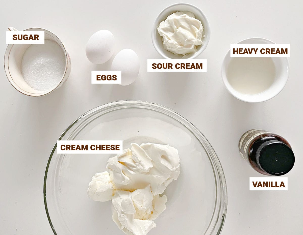 Bowls on white surface containing ingredients for vanilla cheesecake filling.