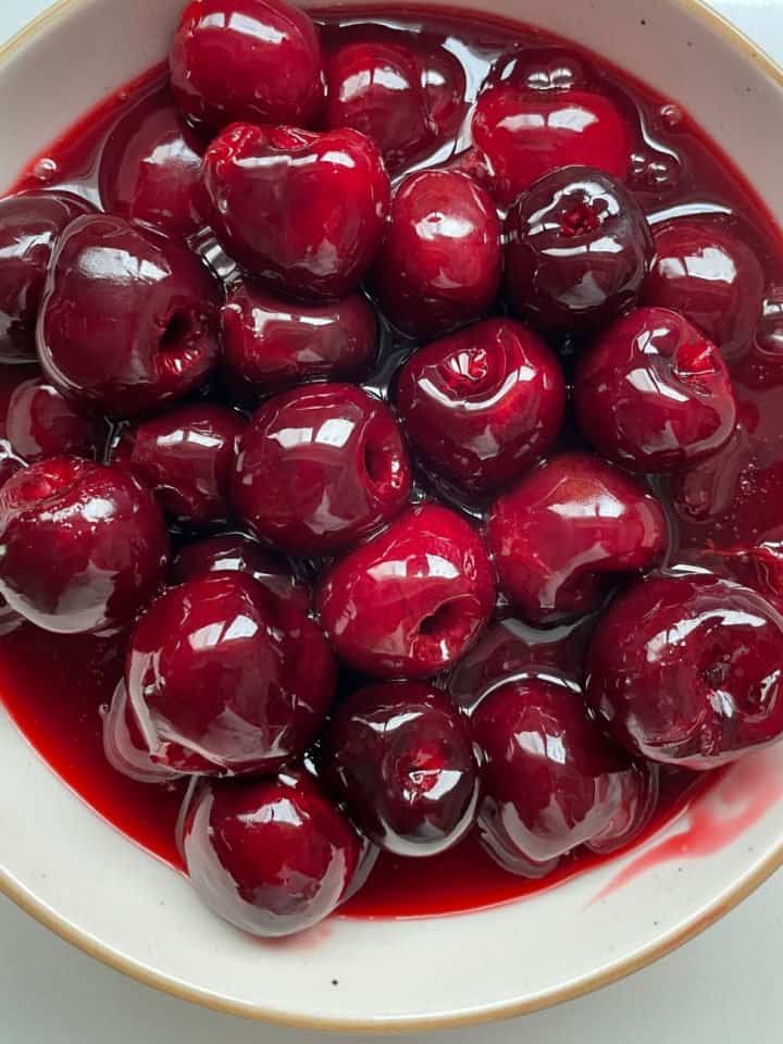 White bowl with whole cherry sauce.