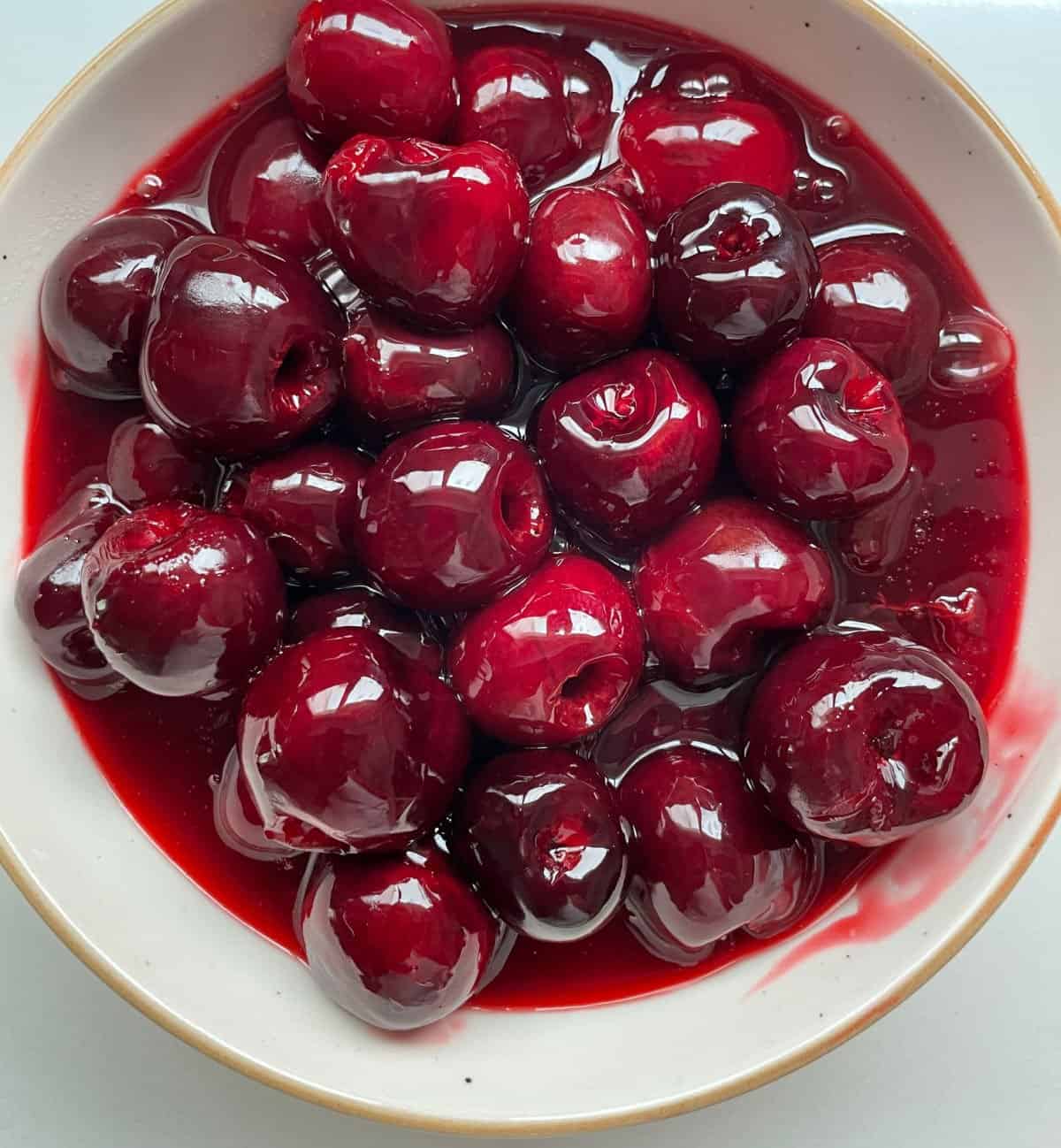 White bowl with whole cherry sauce.