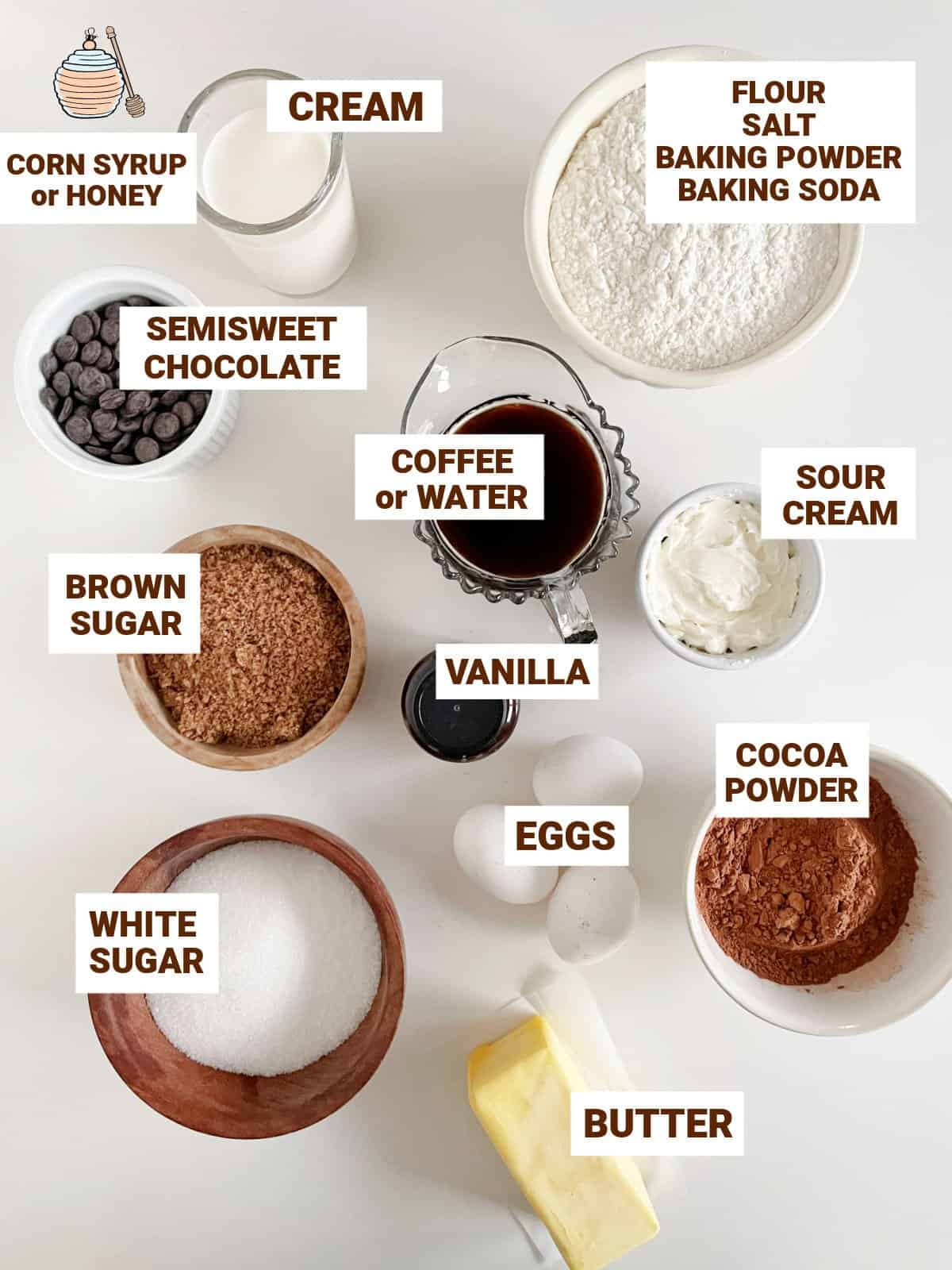 Ingredients for glazed chocolate cake in bowls on white table including cocoa, butter, cream, flour, milk, sugars, coffee, vanilla, sour cream.