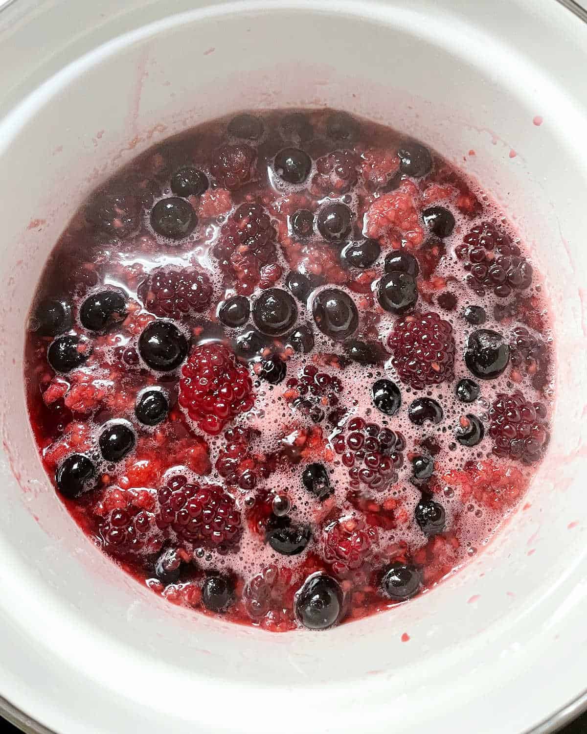 White saucepan with berries and simple syrup. 