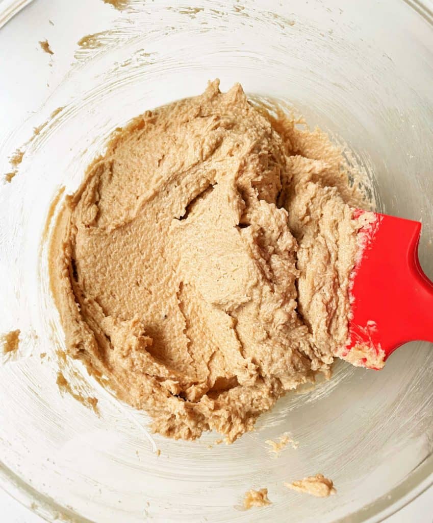 Glass bowl with oatmeal cookie dough. Red spatula.