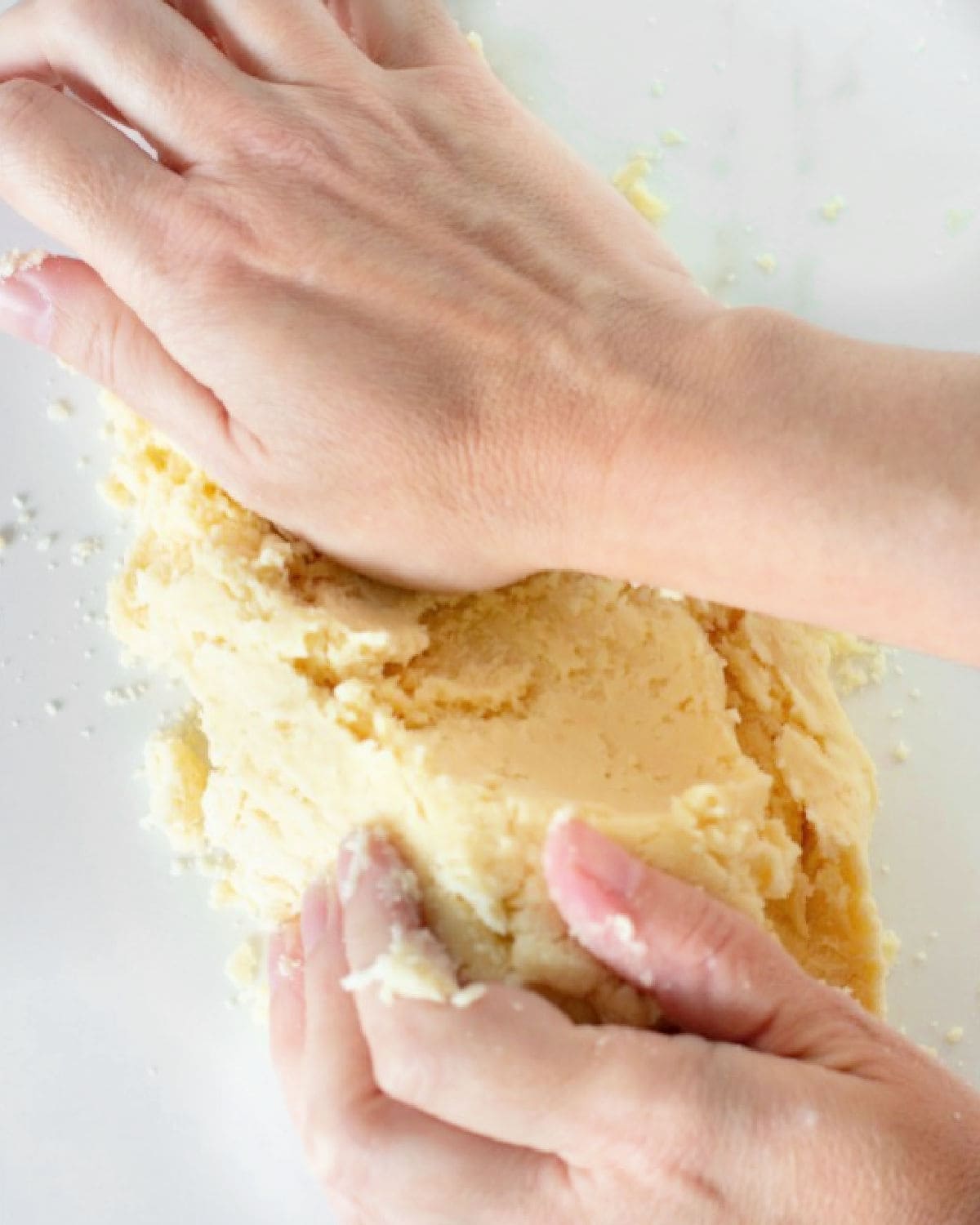 Gathering pie dough by fraisage method on white marble.