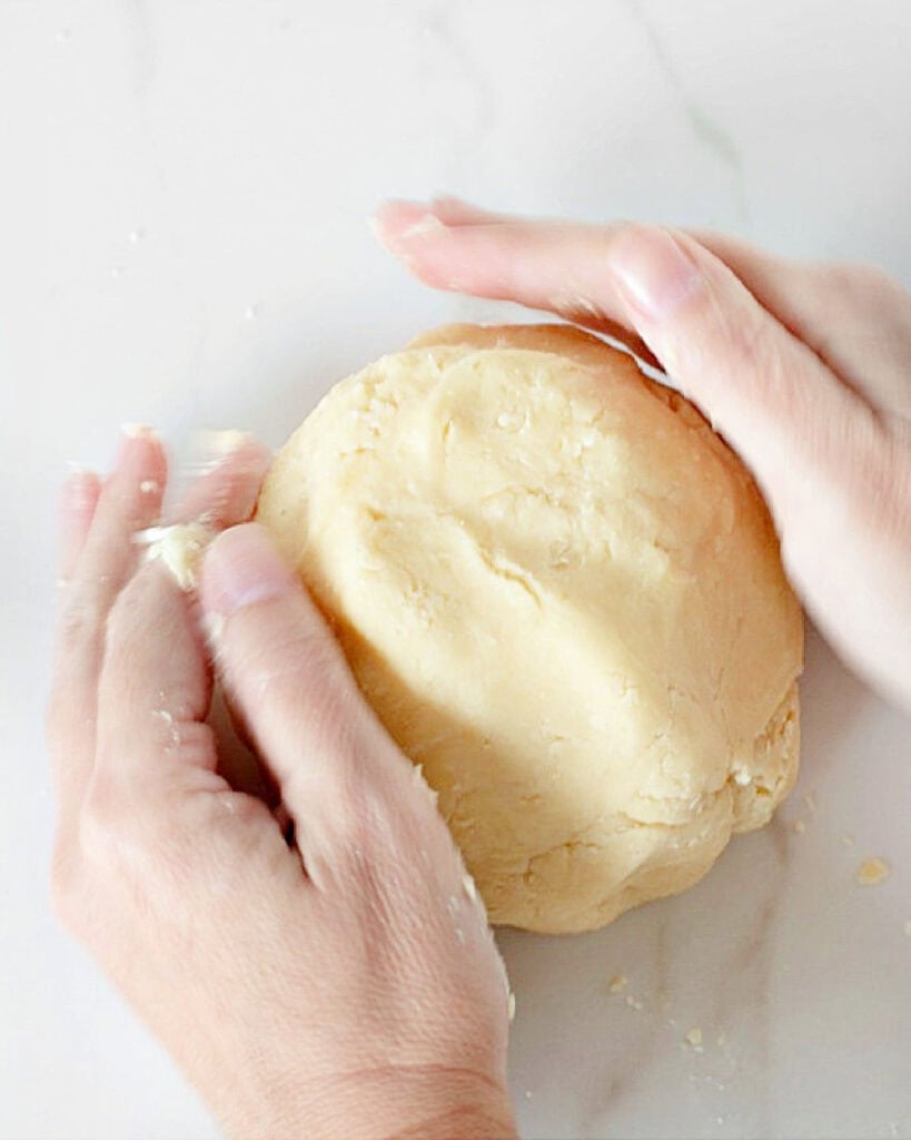 Forming a disc of pasta frolla. White marble background.