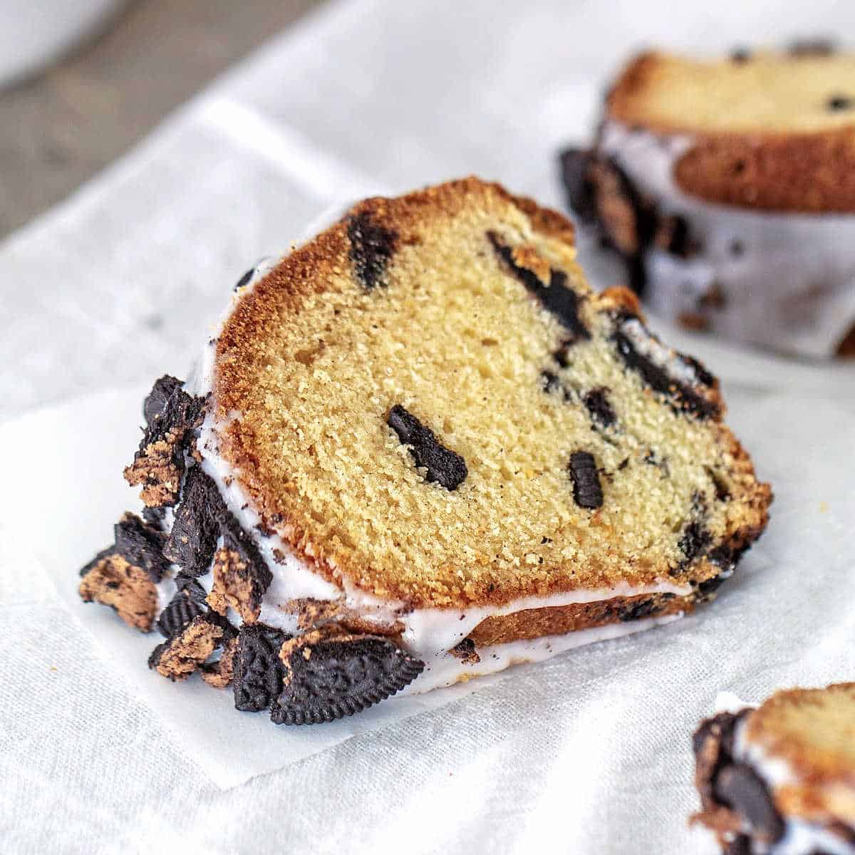 Slices of oreo bundt cake with glaze on white parchment paper.