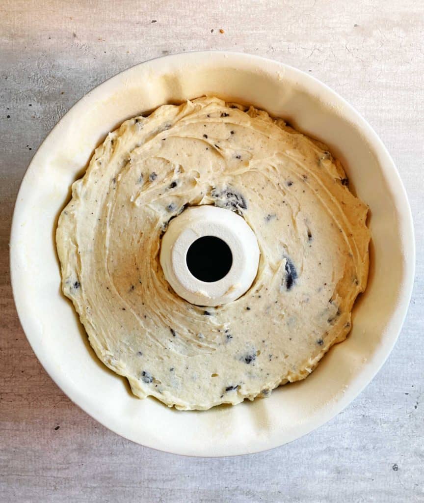 Top view of unbaked vanilla oreo cake batter in white bundt pan on grey surface.