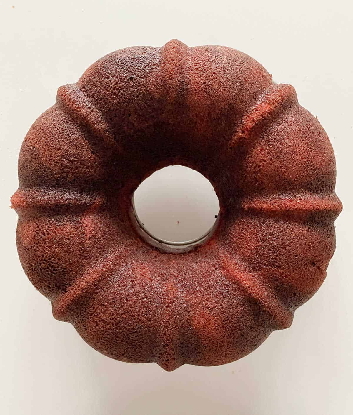 Whole red velvet bundt cake before frosting. View from above. White surface.