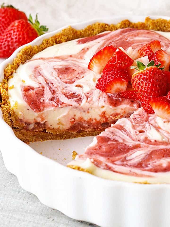 White ceramic dish with eaten strawberry cheesecake pie topped with fresh strawberries.