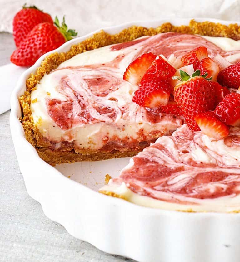 White ceramic dish with eaten strawberry cheesecake pie topped with fresh strawberries.