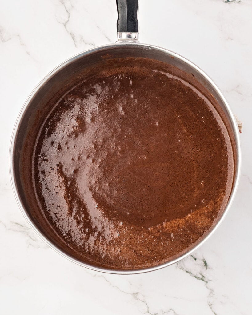 Saucepan with chocolate mixture. White marbled surface.