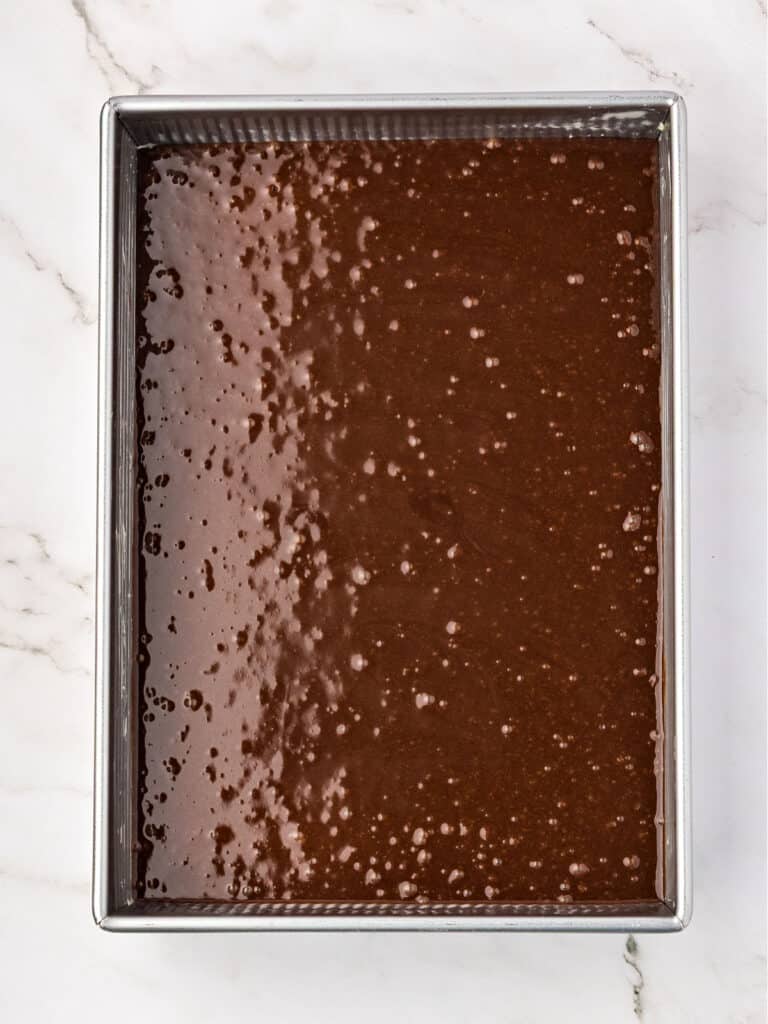 Chocolate cake batter in a rectangular metal pan. Marbled background.