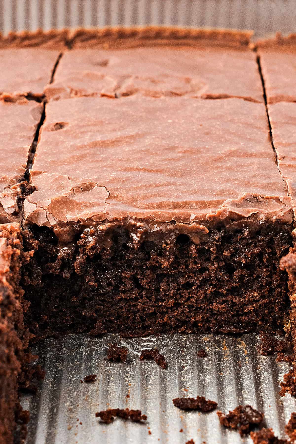 Metal pan with iced chocolate sheet cake. Slice missing.