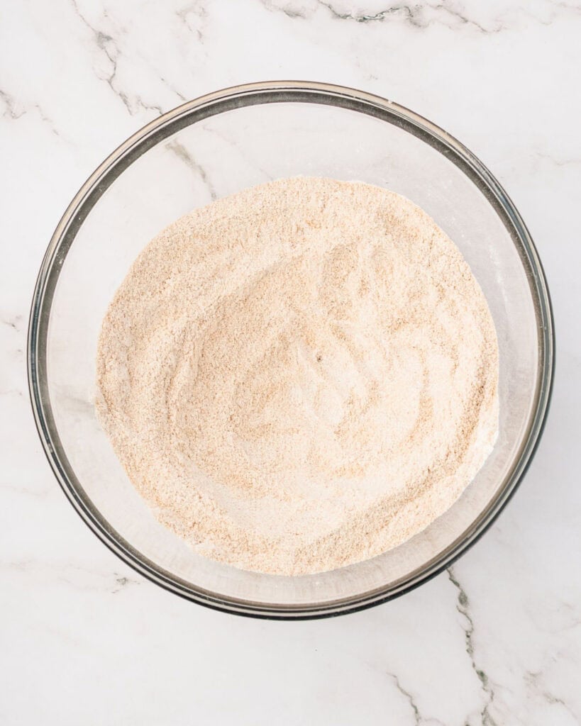 Dry ingredients for cake in a glass bowl. White marbled surface. 