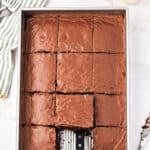 Marbled background with frosted chocolate rectangular cake in metal pan.