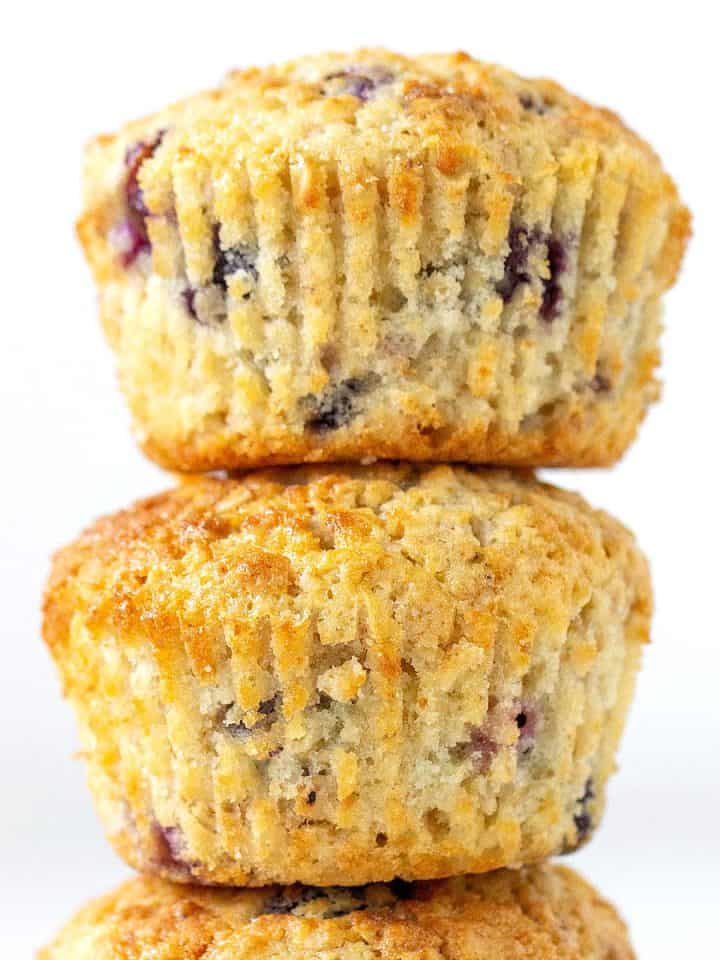 Close up of blueberry oat muffins in a stack with white background.