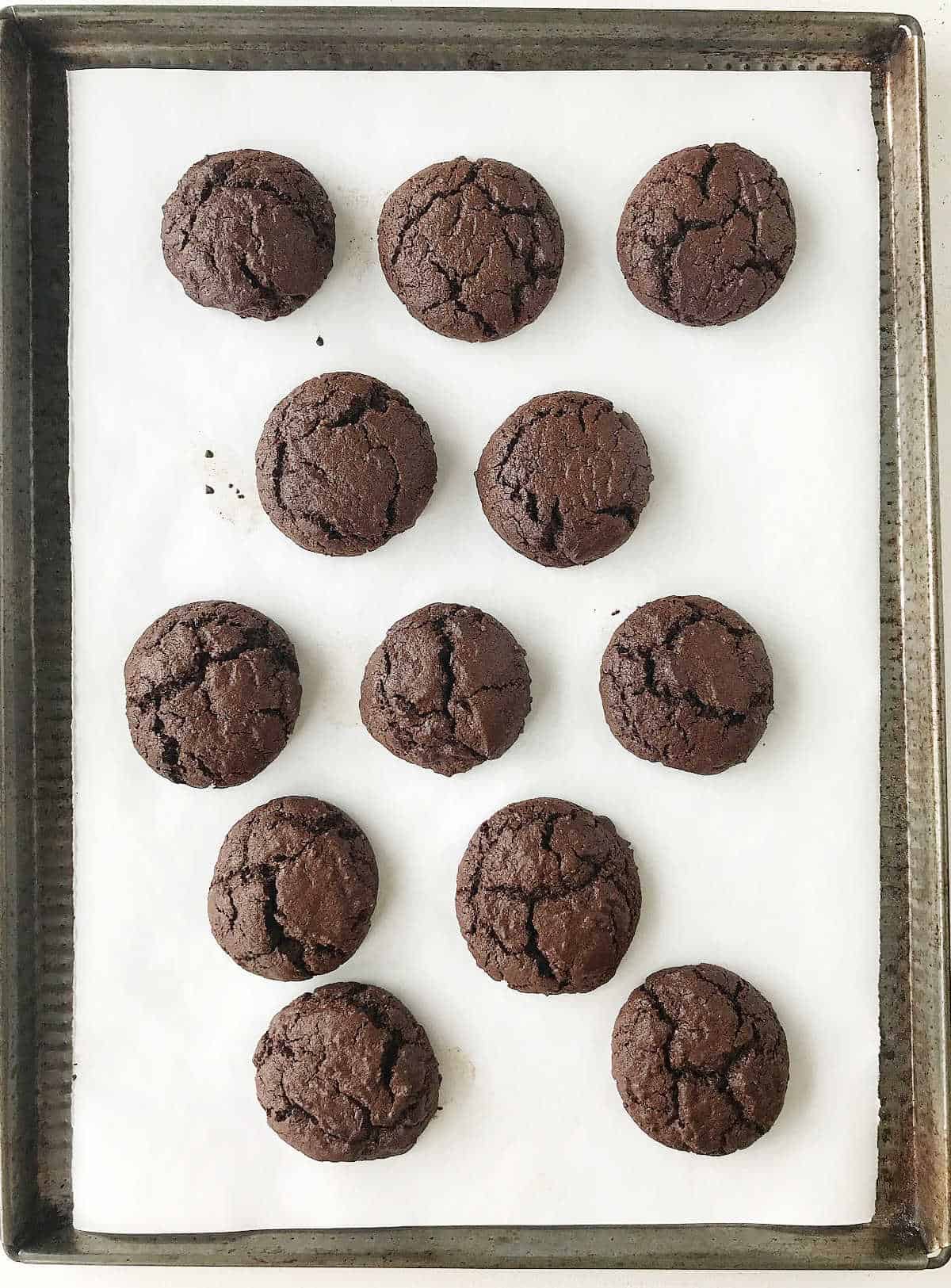 Parchment paper on cookie sheet with baked chocolate whoopie pies.