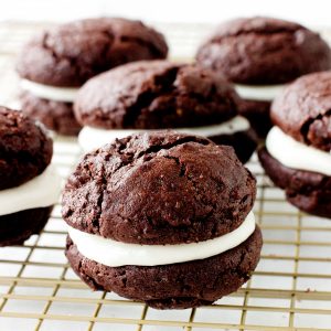 Several chocolate whoopie pies on a gold wire rack.