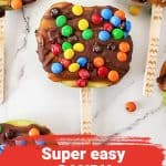 Close up of chocolate and candy covered apple slices on a stick. Red text overlay.