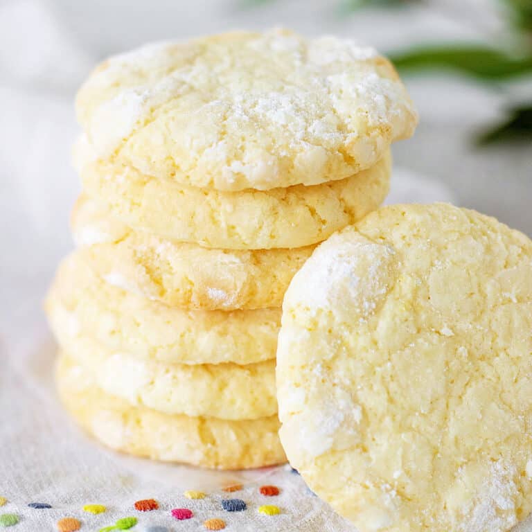 Several lemon crinkle cookies stacked on a white napkin with colored dots.