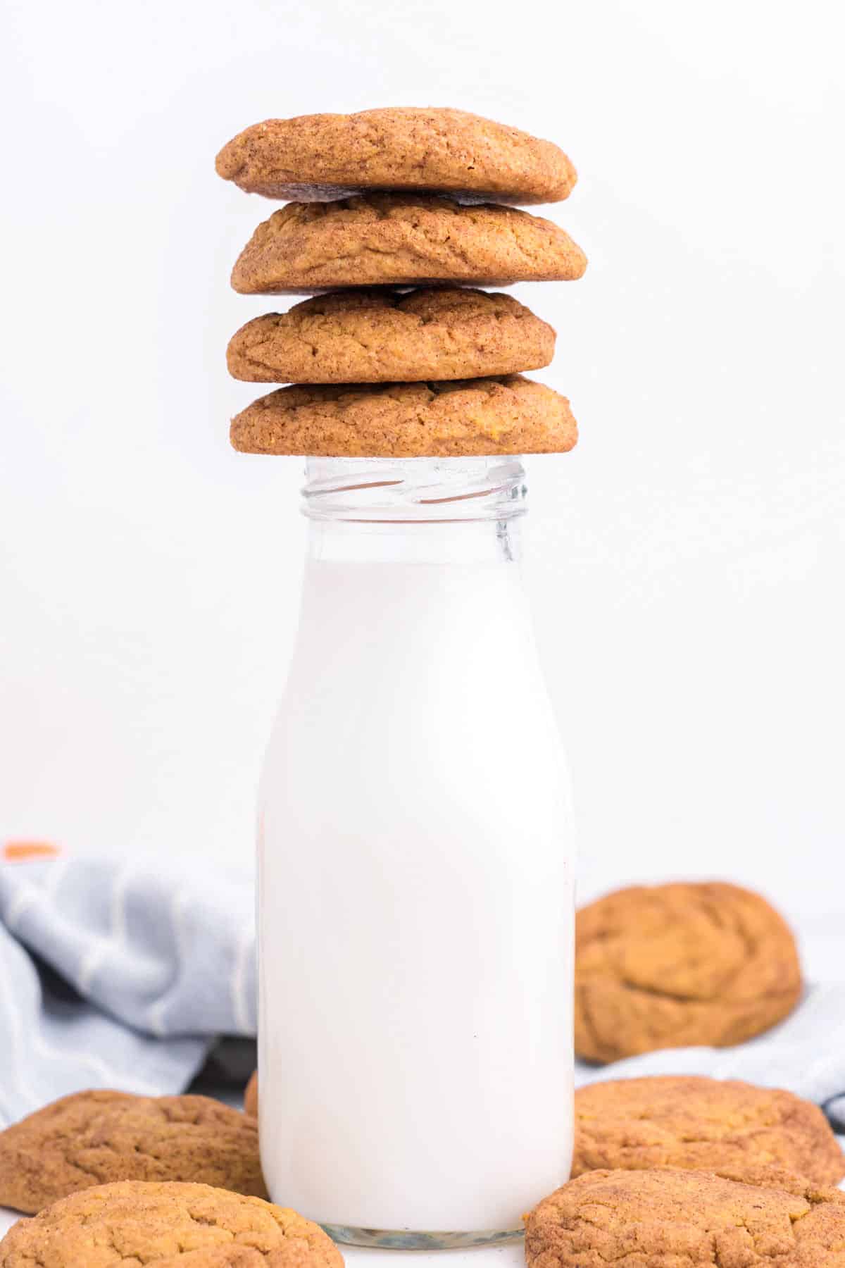 Milk bottle with pumpkin cookies on top and around. White background. 