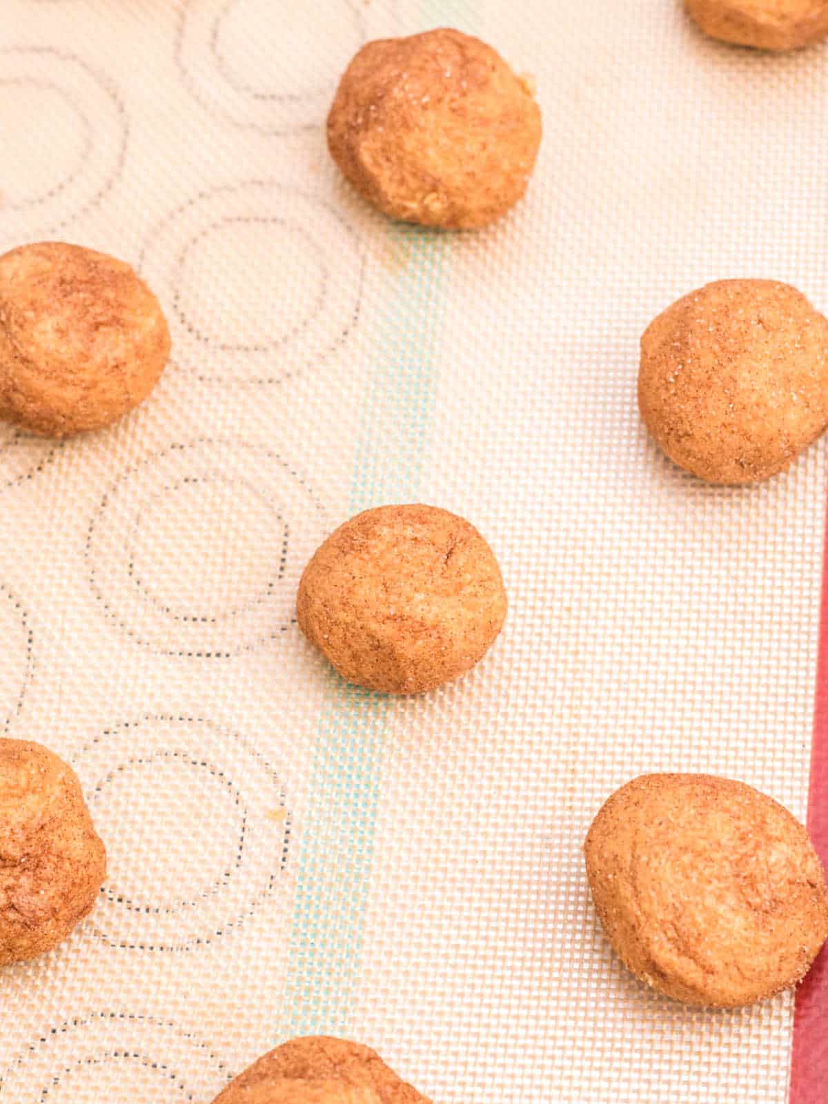 Silpat mat with unbaked pumpkin cookie dough balls.