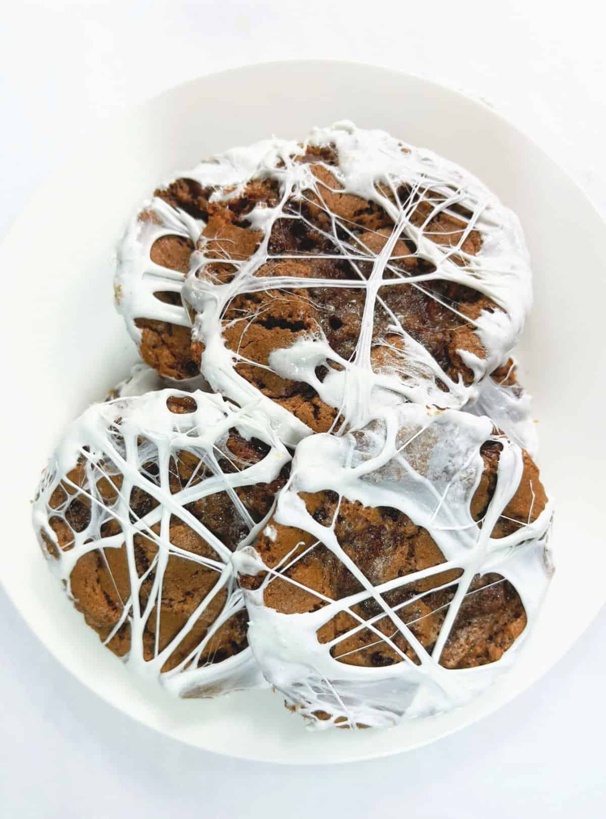 White plate on white surface with several marshmallow chocolate cookies. 