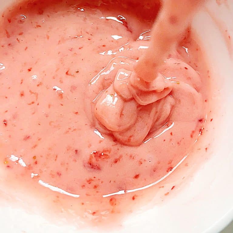 Thick strawberry glaze being poured into a white bowl. Close up image.