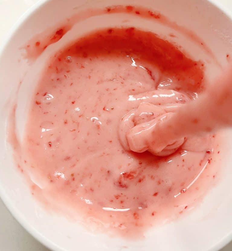 Strawberry glaze being poured into a white bowl.