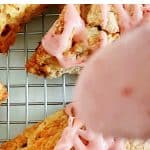 Close up of strawberry glaze being drizzled over scones. Red and white text overlay.