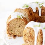 Partial view of glazed bundt cake on a white cake stand. White background