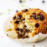 Close up of single bitten muffins with chocolate chips on a white background.