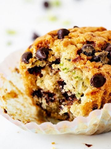 Close up of single bitten muffins with chocolate chips on a white background.