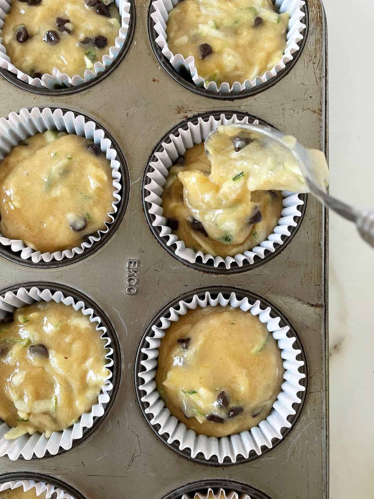 Close up of zucchini chocolate chip muffin batter in muffin pan.