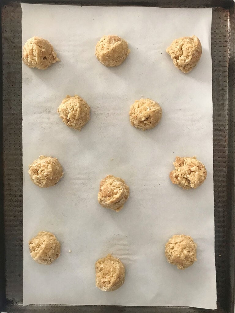 Overview of metal sheet pan with unbaked oatmeal cookies.