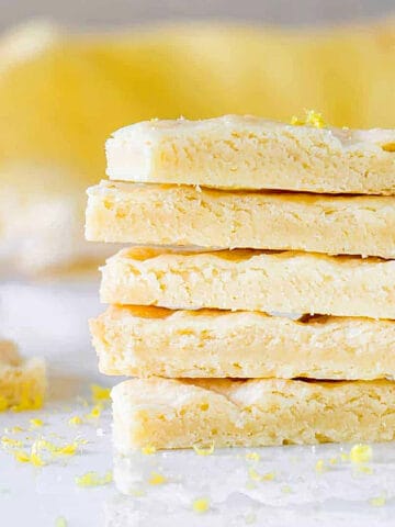 Stack of several lemon shortbread sticks with yellow background and white marble surface.