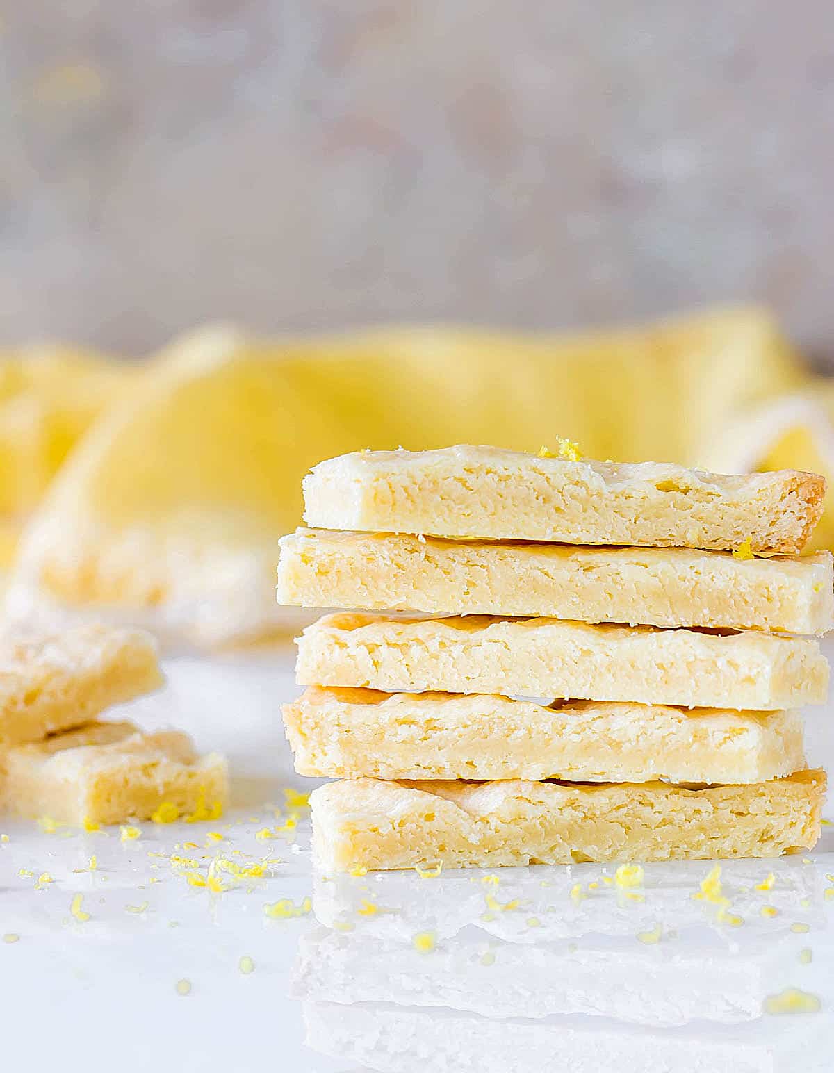 Grey and yellow background with stack of five shortbread fingers on a white surface.