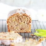 Apple loaf cake on a black cooling rack, slices and cut green apple around.