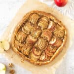Whole baked apple galette on beige parchment paper. Apple halves. Top view.