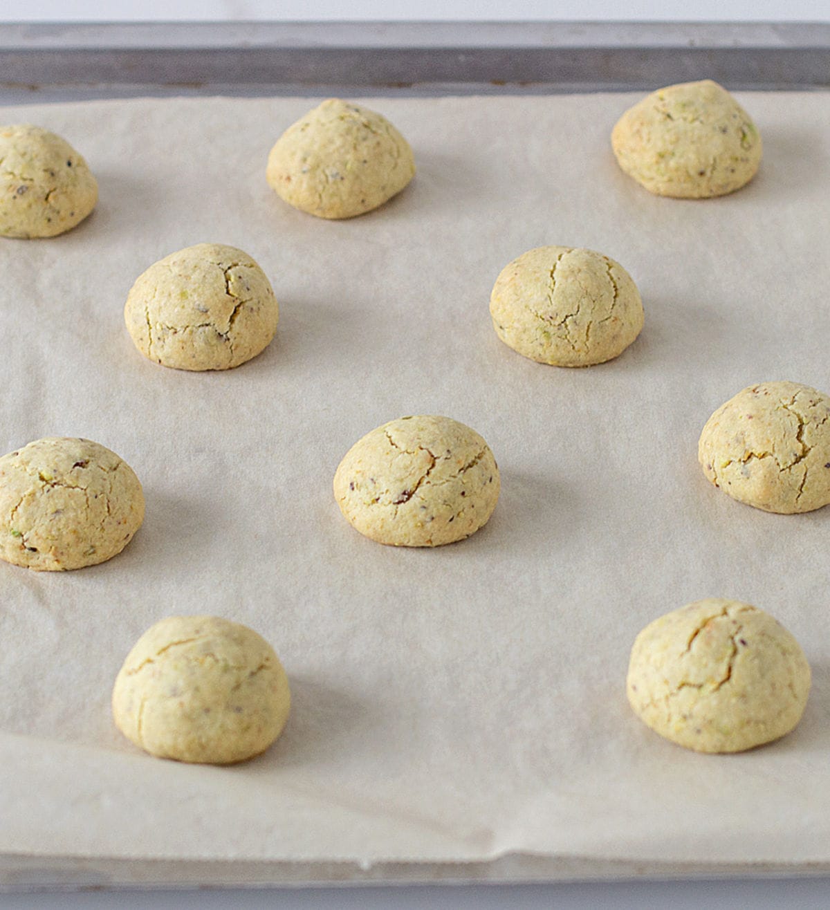 Baked pistachio balls on parchment paper.