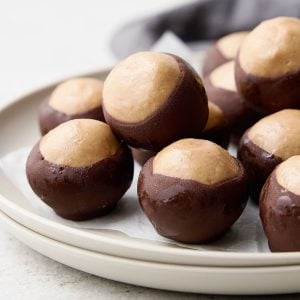 Stack of grey plates with buckeye candy balls. A dark grey cloth in the background.