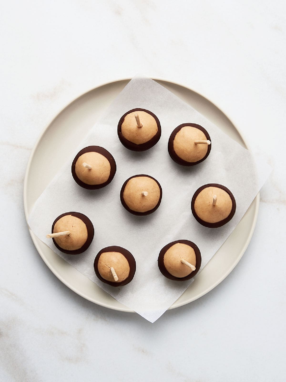 Buckeye candy balls on a white plate on white marble.