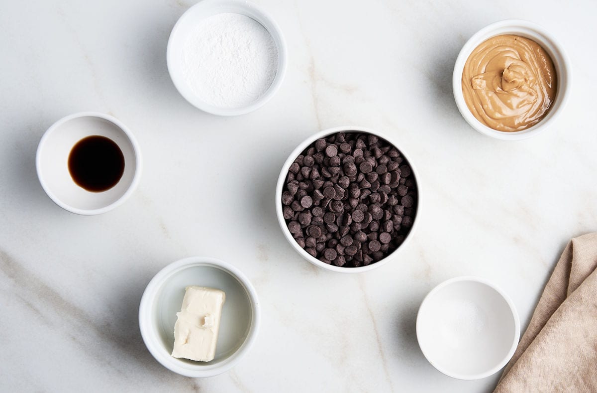 Buckeye candy ingredients in white bowls on a white marbled surface.