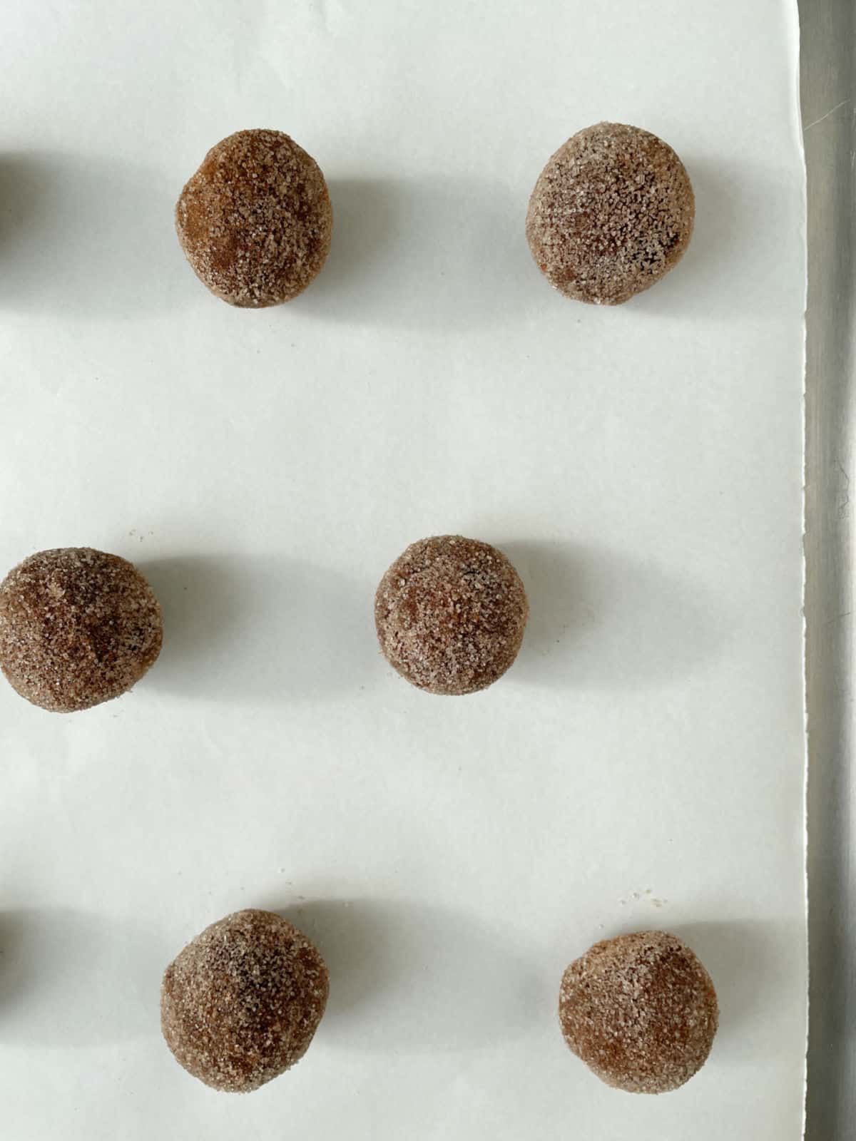 Parchment paper with chocolate cookie balls before baking.