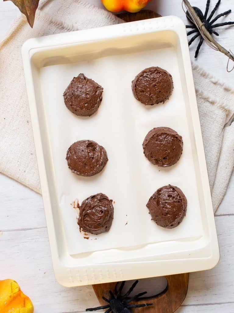 White baking tray with chocolate whoopie pie dough mounds.