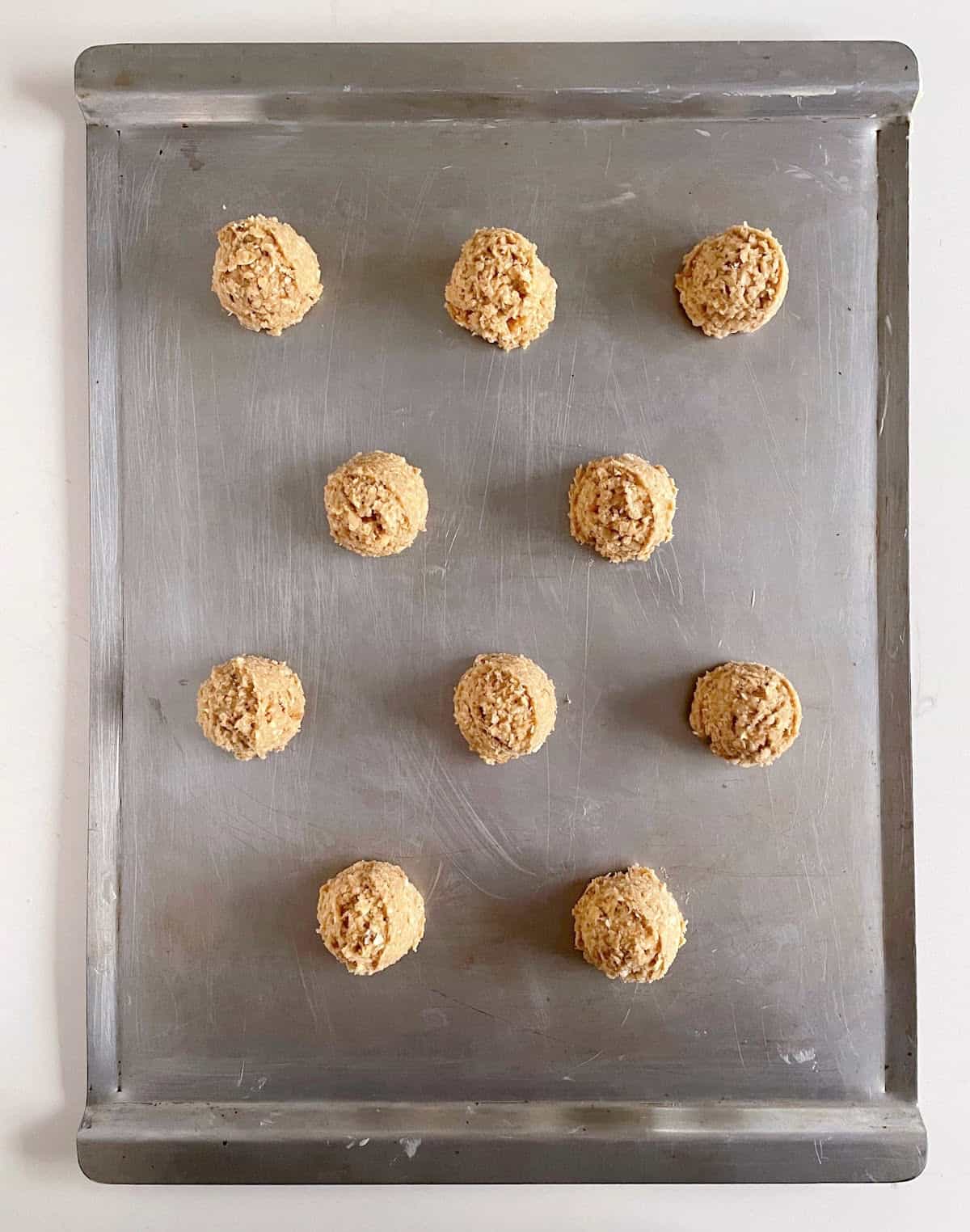 Metal cookie sheet with scoops of oatmeal cookie dough. Top view. 
