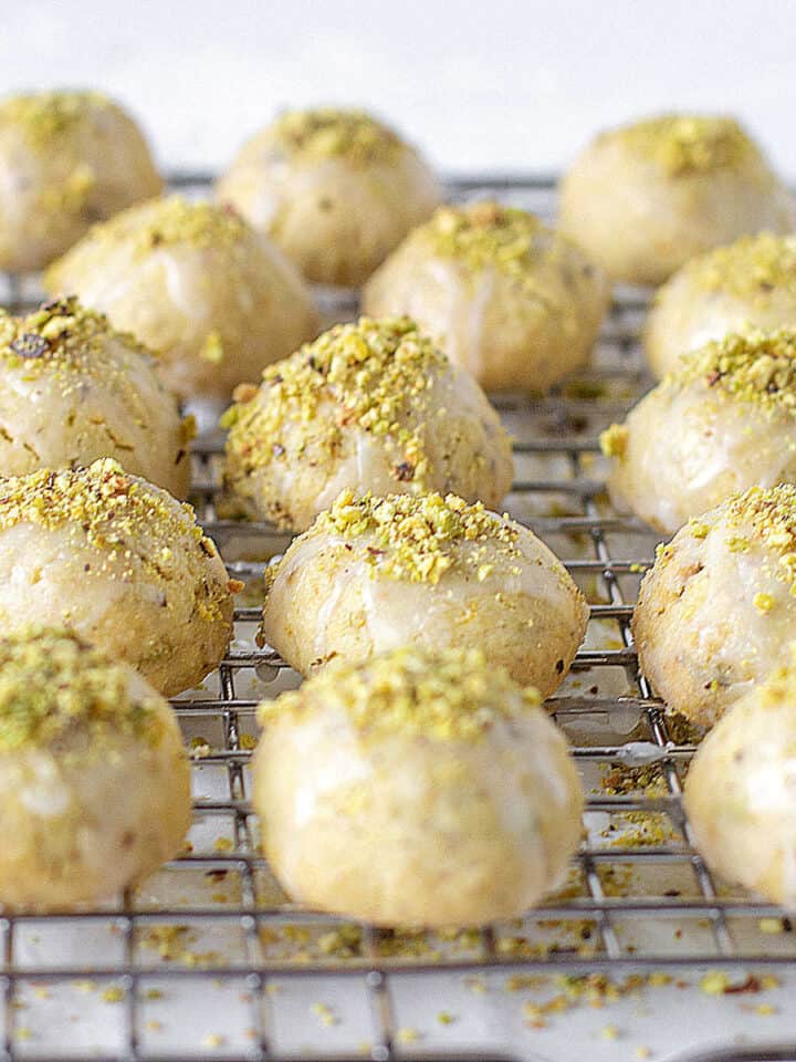Rows of glazed pistachio cookies on a wire rack.